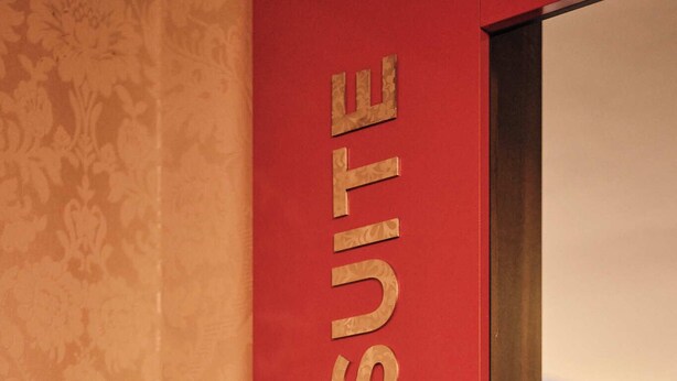 Un mur rouge sur lequel est inscrit en lettres dorées le texte « HERO SUITE ».