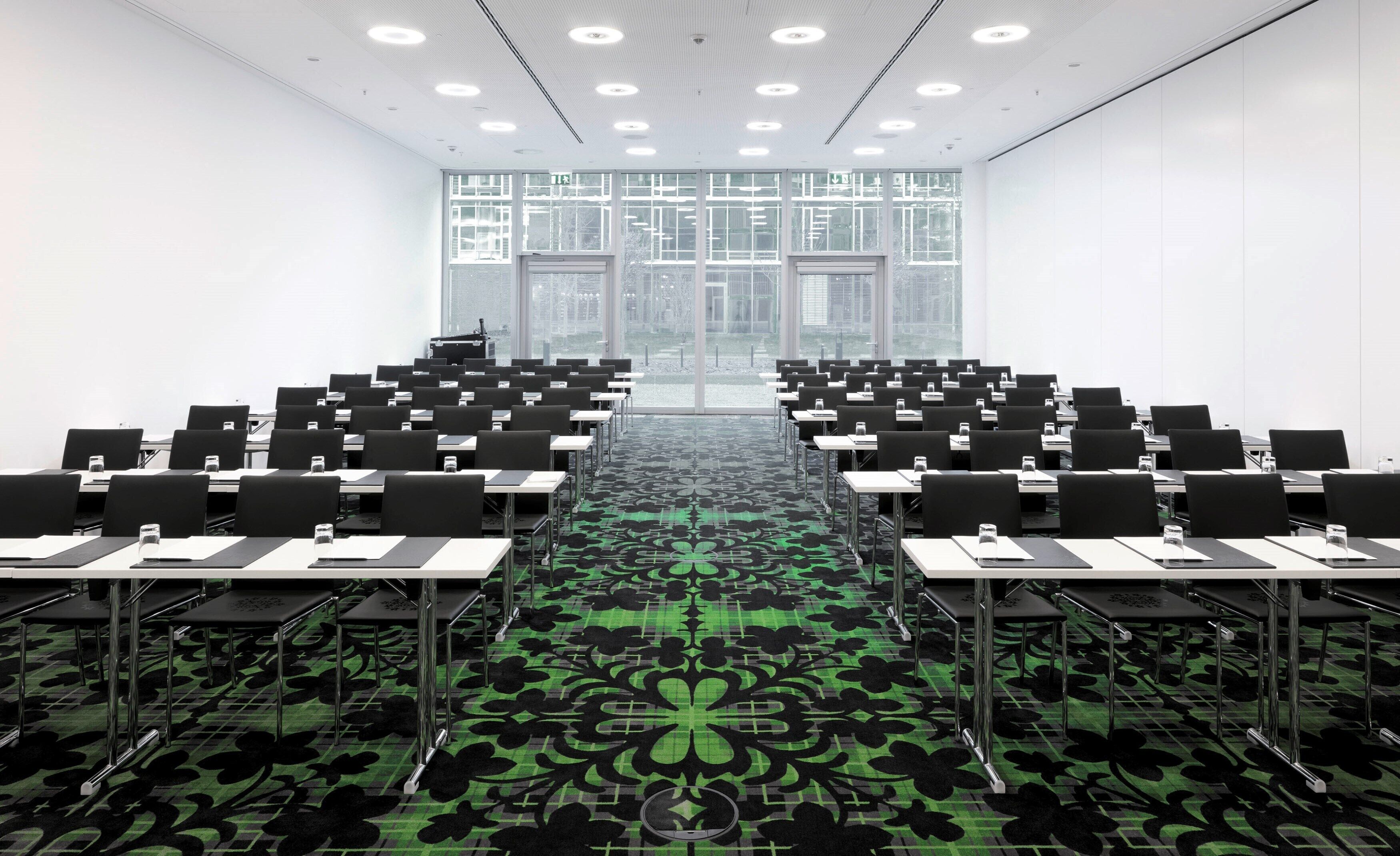 A conference room with a long table, multiple chairs, and a patterned carpet.