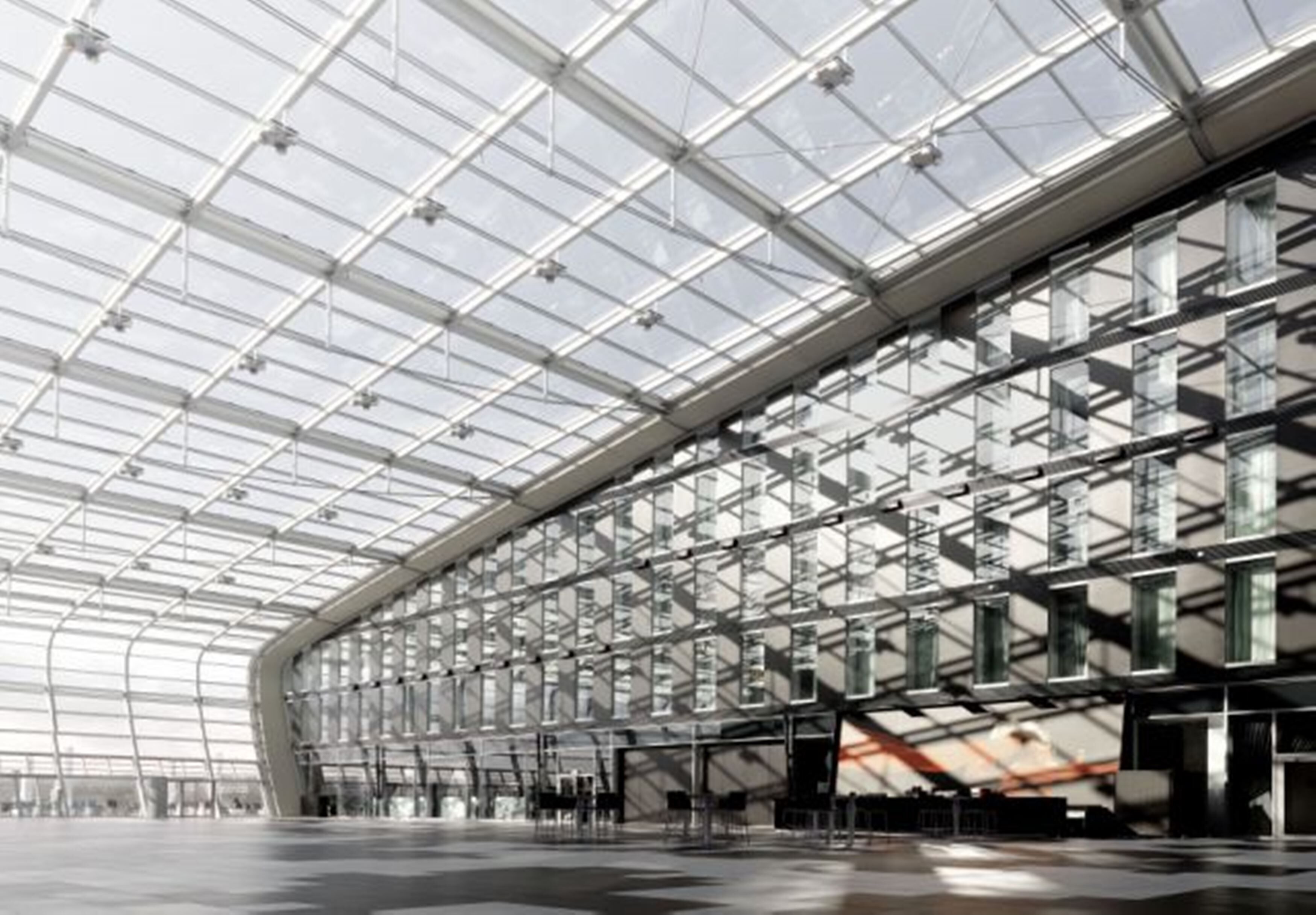 A large, modern building with a glass facade and a curved roof structure.