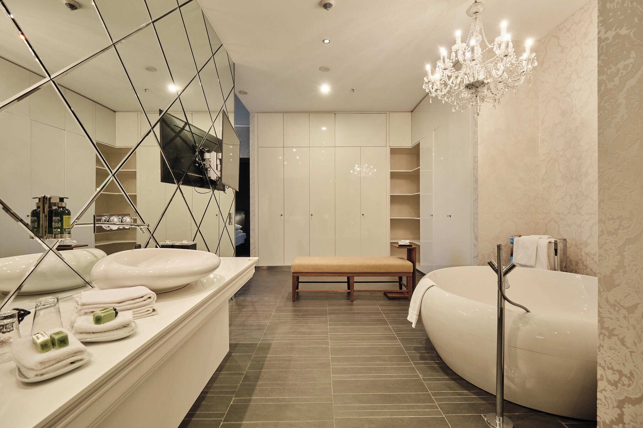 Un baño moderno con una bañera independiente, un banco y un mueble de tocador con espejo y artículos de aseo.