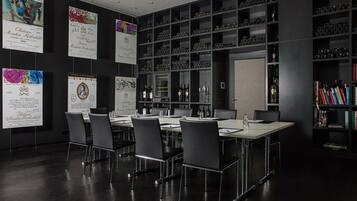 Un salón de conferencias con una larga mesa, sillas y una estantería con diversos objetos.