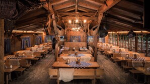 A rustic wooden interior with high ceilings, wooden benches, tables with checkered tablecloths, and a chandelier. - Kameha Grand Bonn (Bonn)
