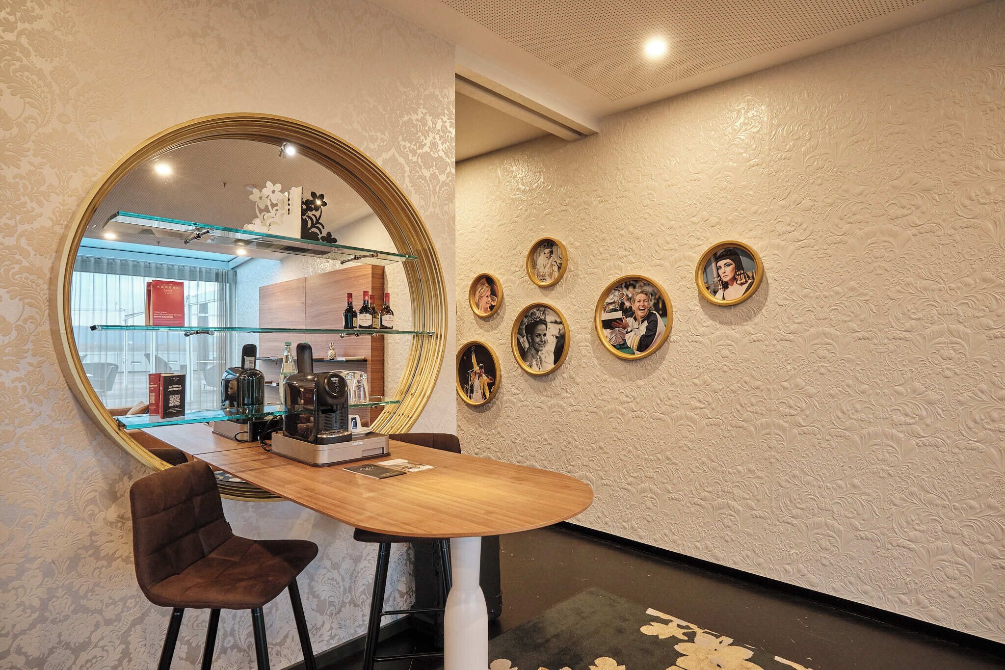 A modern interior with a round mirror, a wooden desk, and framed pictures on the wall.