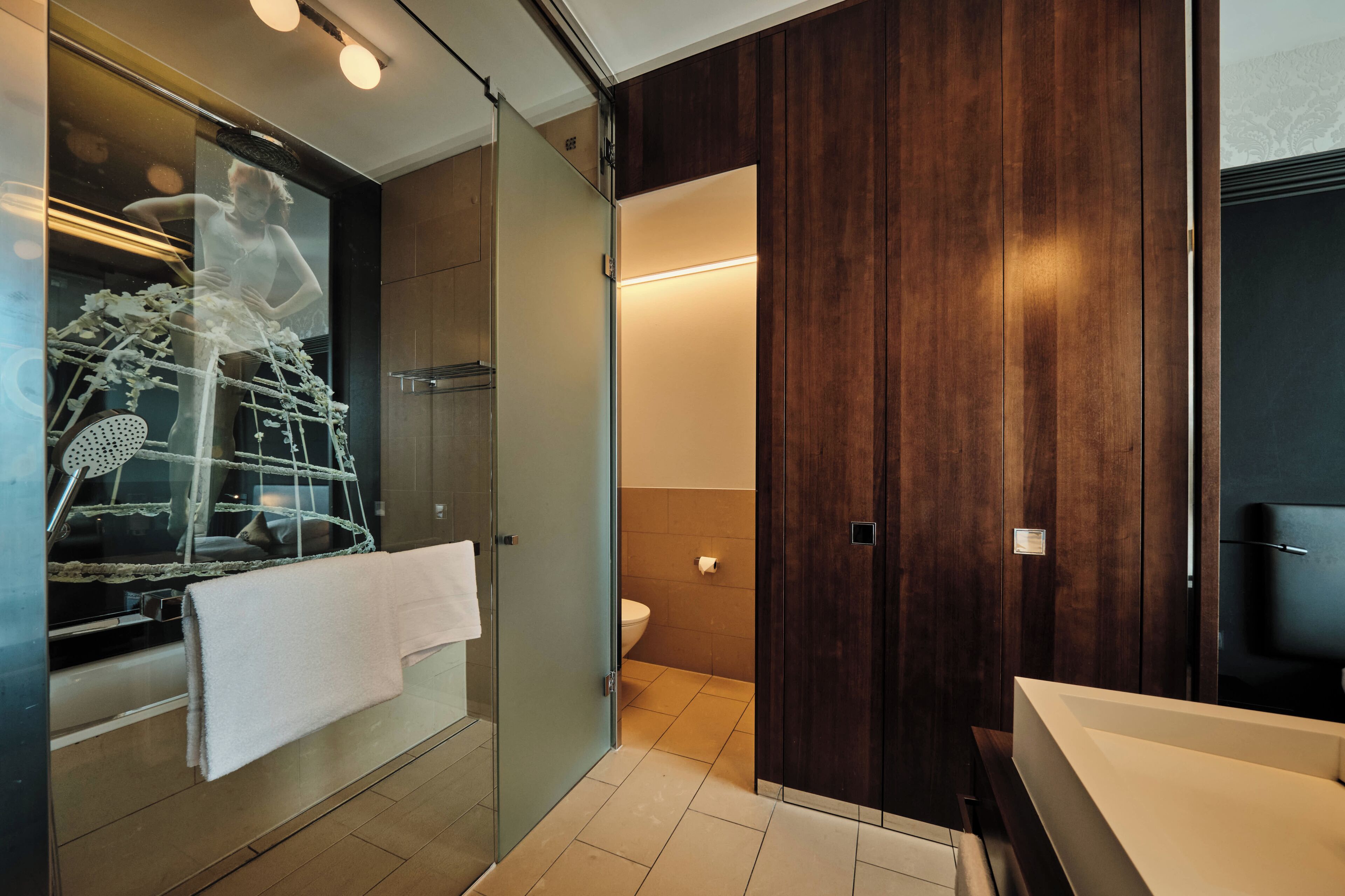 Ein modernes Badezimmer mit einer Glasdusche, einem Holzkosmetikschrank und einer Toilette.