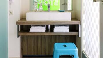 A bathroom with a white sink, a mirror, and a blue stool.
