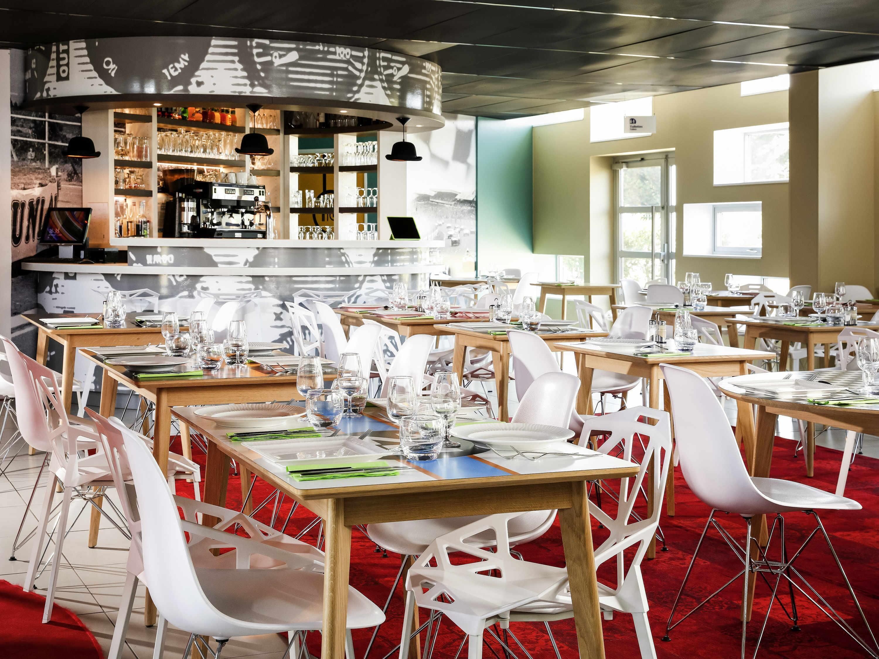 Un restaurante con varias mesas, sillas y una zona de bar con estantes llenos de copas y botellas.