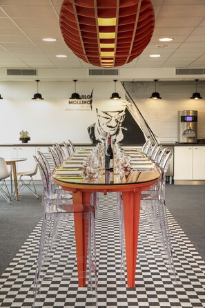 A conference room with a checkered floor, a round table with chairs, and a large red ceiling light fixture. - ibis Styles Le Mans Sud Mulsanne (Mulsanne)