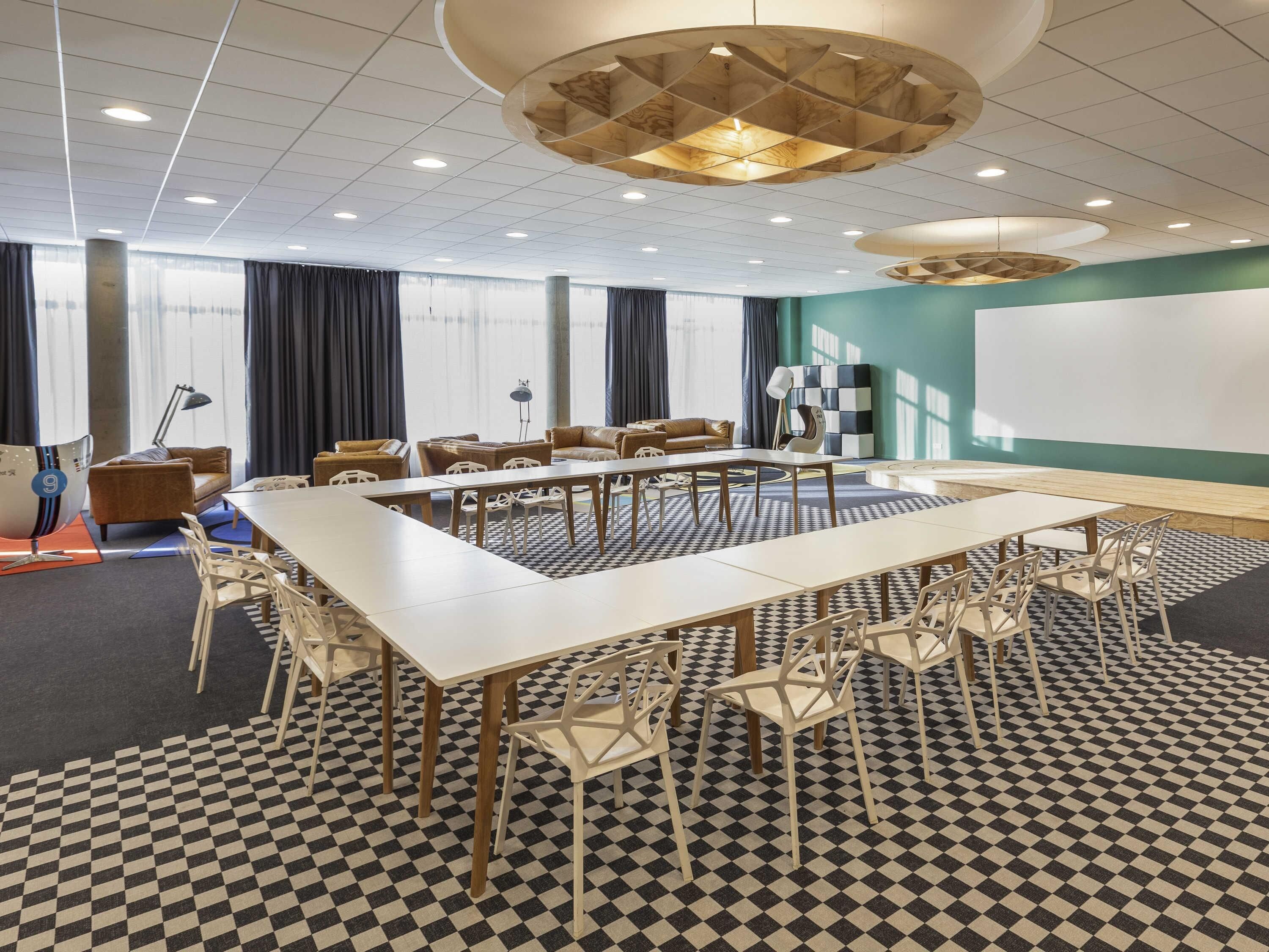 A conference room with a large table, chairs, a projector screen, and a patterned floor.
