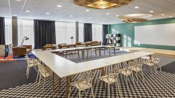 A conference room with a large table, chairs, a projector screen, and a patterned floor.