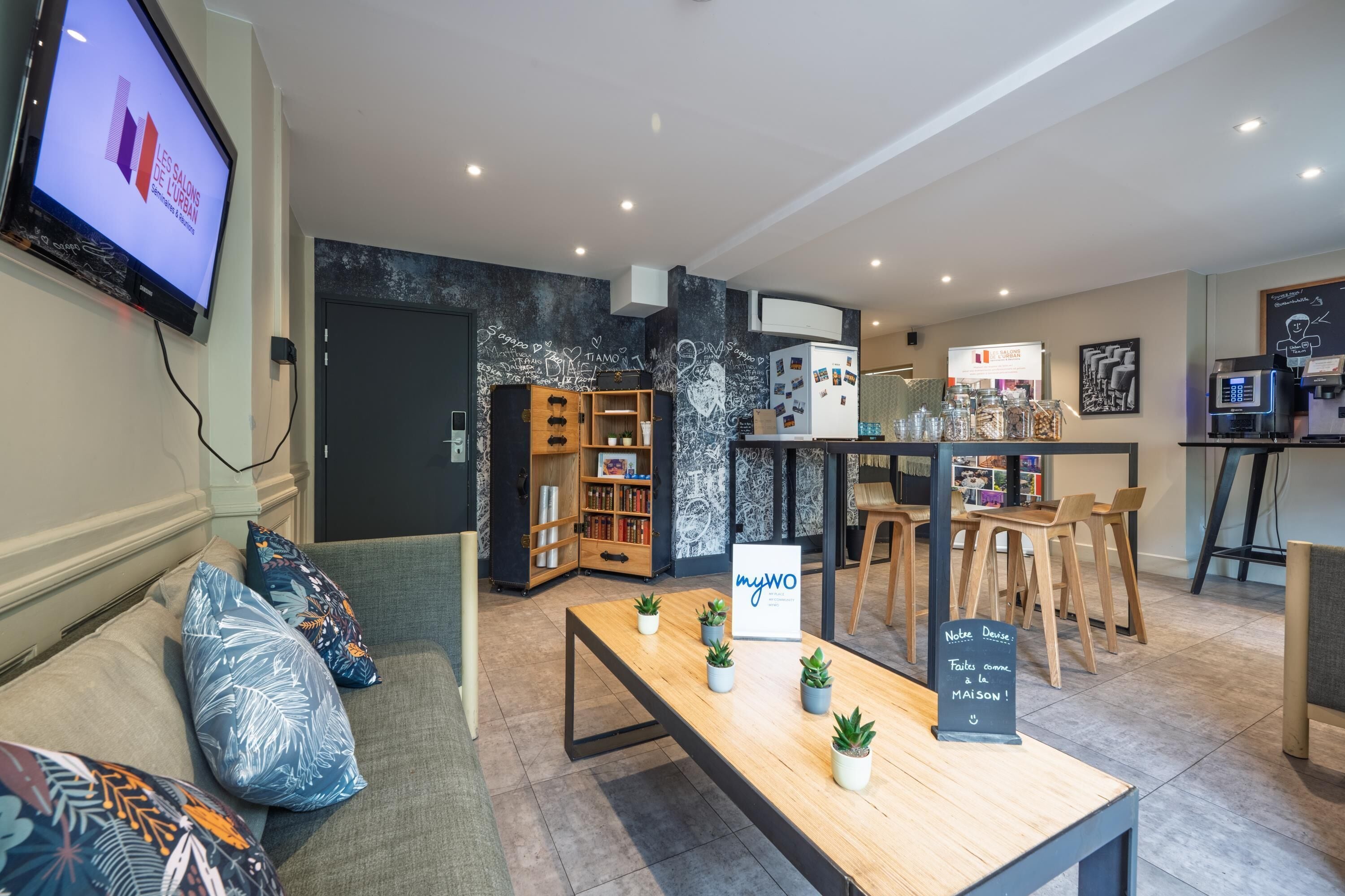 A modern interior with a reception desk, seating area, and a coffee bar.