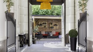 A hallway with a modern sofa set, a potted plant, and a large yellow pendant light. - Best Western Urban Hotel  (Lille)