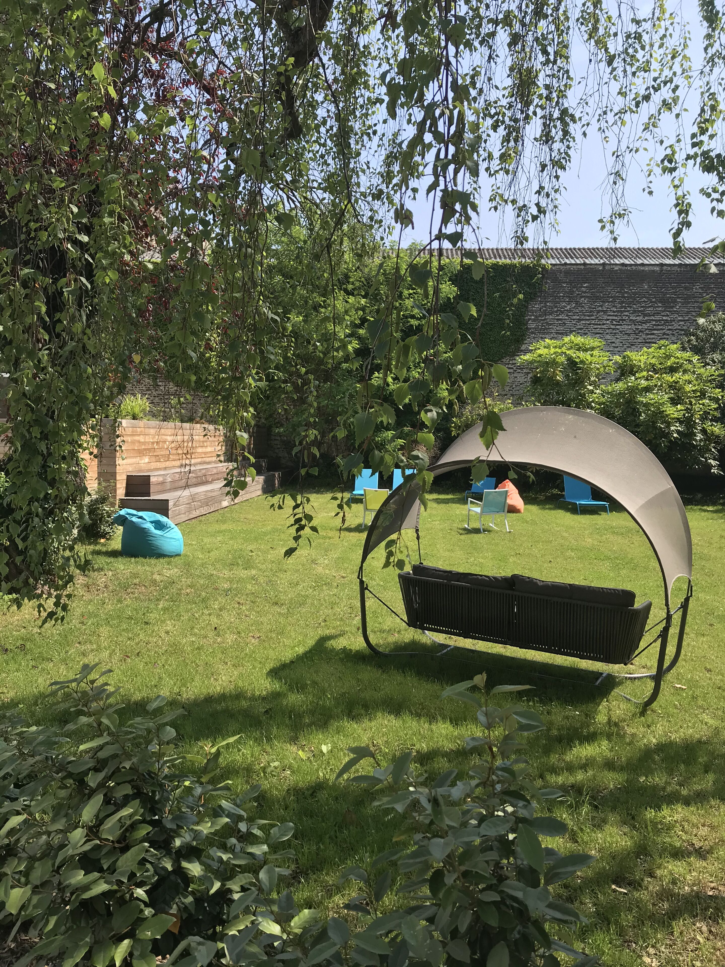 Un jardín con un columpio y una zona de estar techada.