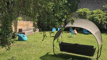 Un jardín con un columpio y una zona de estar techada.