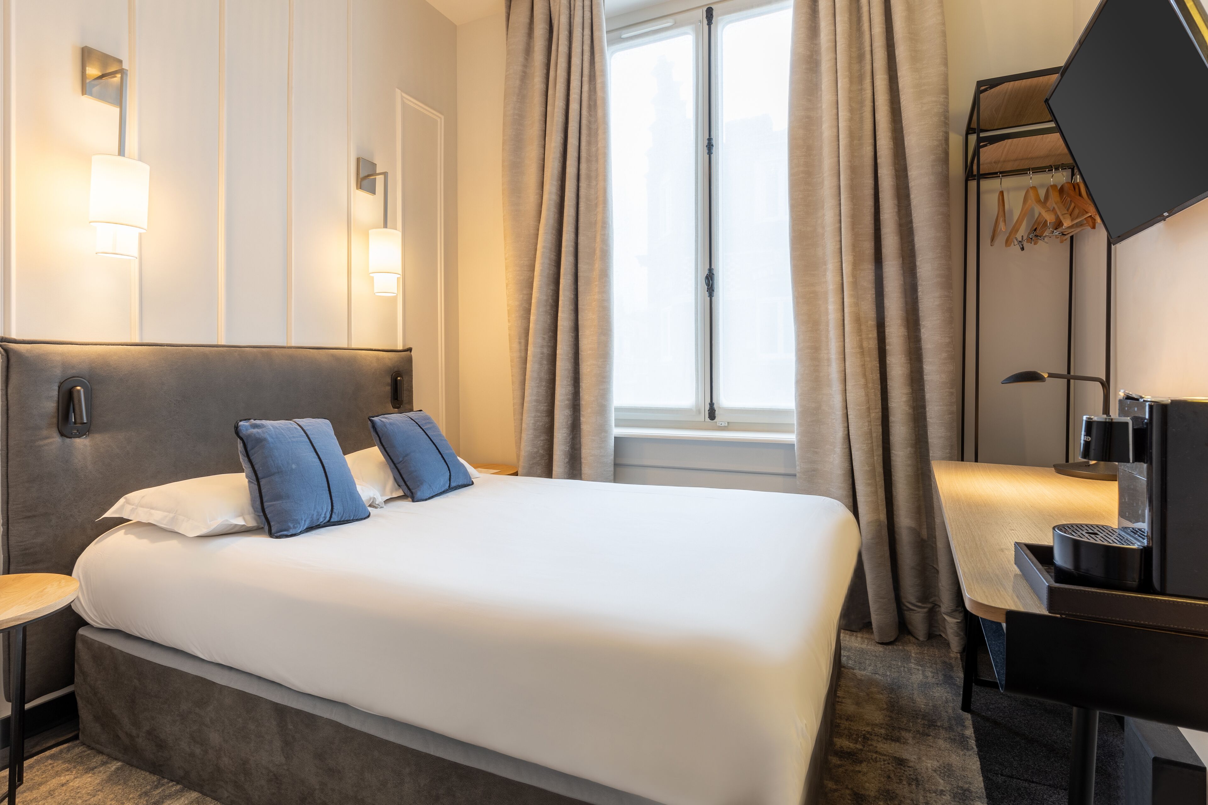 Une chambre d’hôtel avec un grand lit, des tables de chevet, un bureau et une télévision.