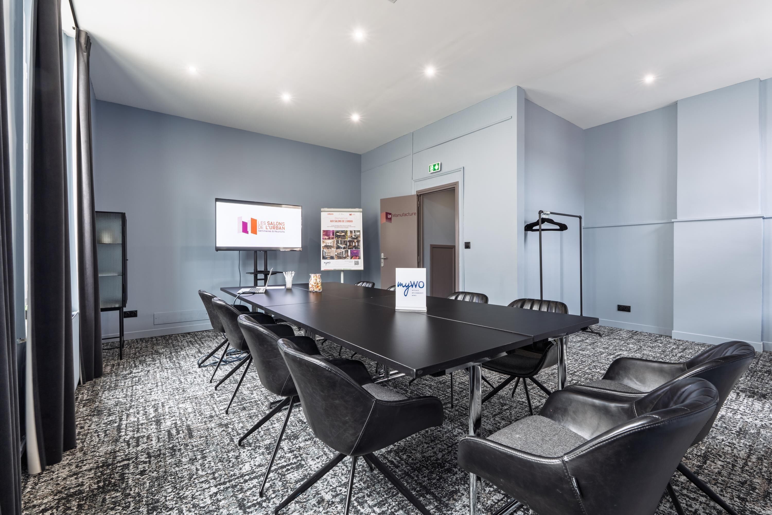 A conference room with a long table, black chairs, a projector screen, and a banner.