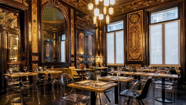 A luxurious dining area with ornate decor, clear chairs, and tables set for a meal. - Best Western Urban Hotel  (Lille)