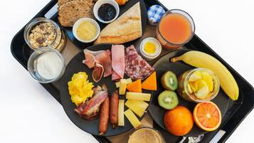 Bandeja de desayuno con diversos alimentos, incluyendo pan, huevos, queso, carnes y frutas.