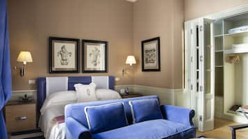 A hotel room with a bed, a blue sofa, a wardrobe, and two wall-mounted lamps.
