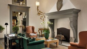 A spacious living room with a fireplace, green and brown leather chairs, a coffee table, and a statue. - Palazzo Vecchietti (Florence)