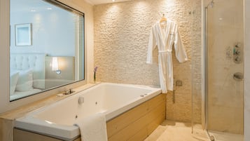 A modern bathroom with a large bathtub, a walk-in shower, and a wooden vanity.