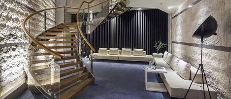 Un interior moderno con una escalera espiral, un conjunto de sofás y una lámpara de pie.