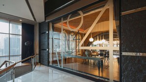 Un moderno vestíbulo de hotel con pared de vidrio, piso de mármol y una escalera.