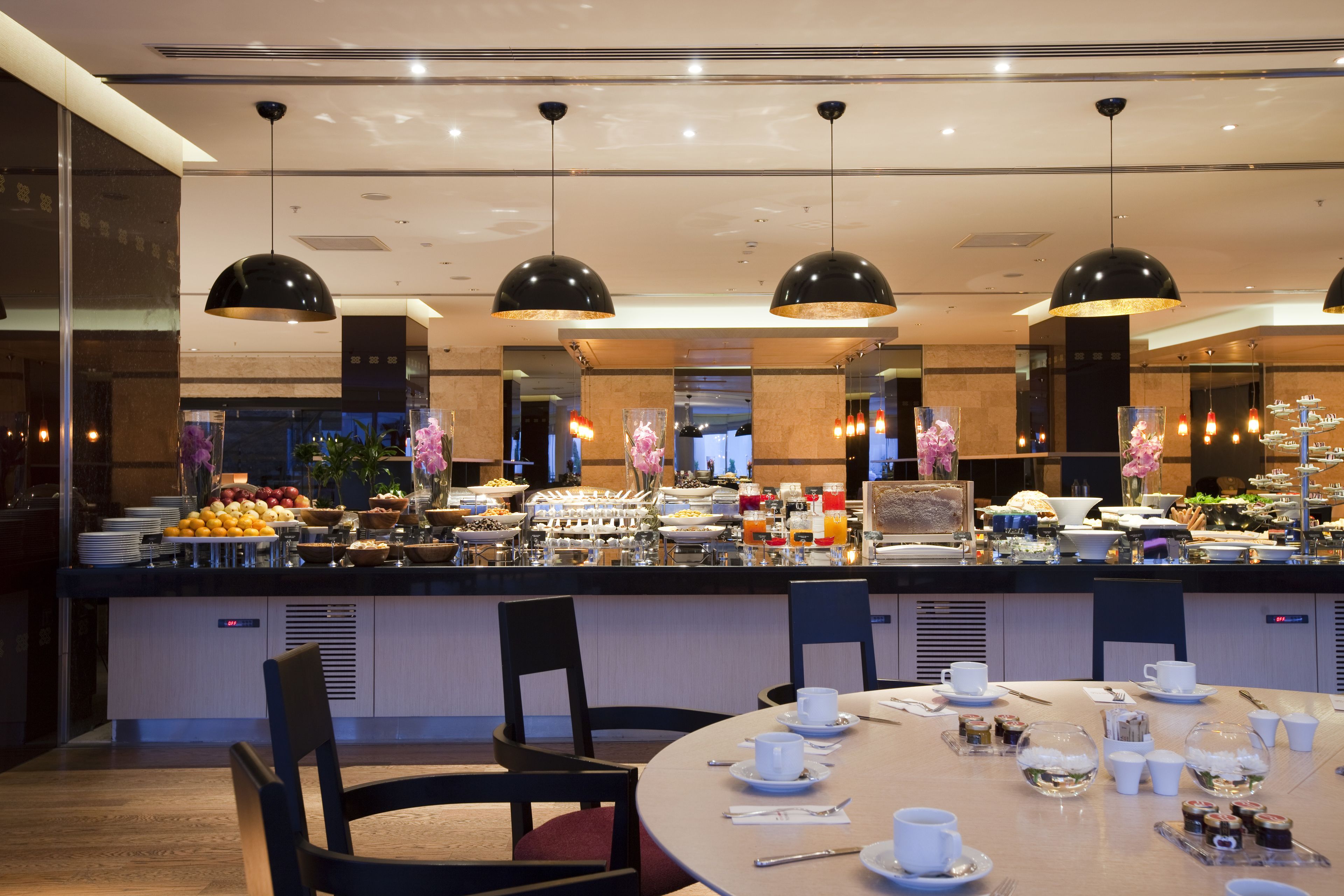 Een ontbijtruimte in een hotel met een buffet, eettafels en stoelen.