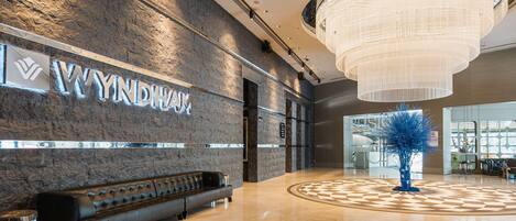 A modern lobby with a stone wall, a bench, and a chandelier.