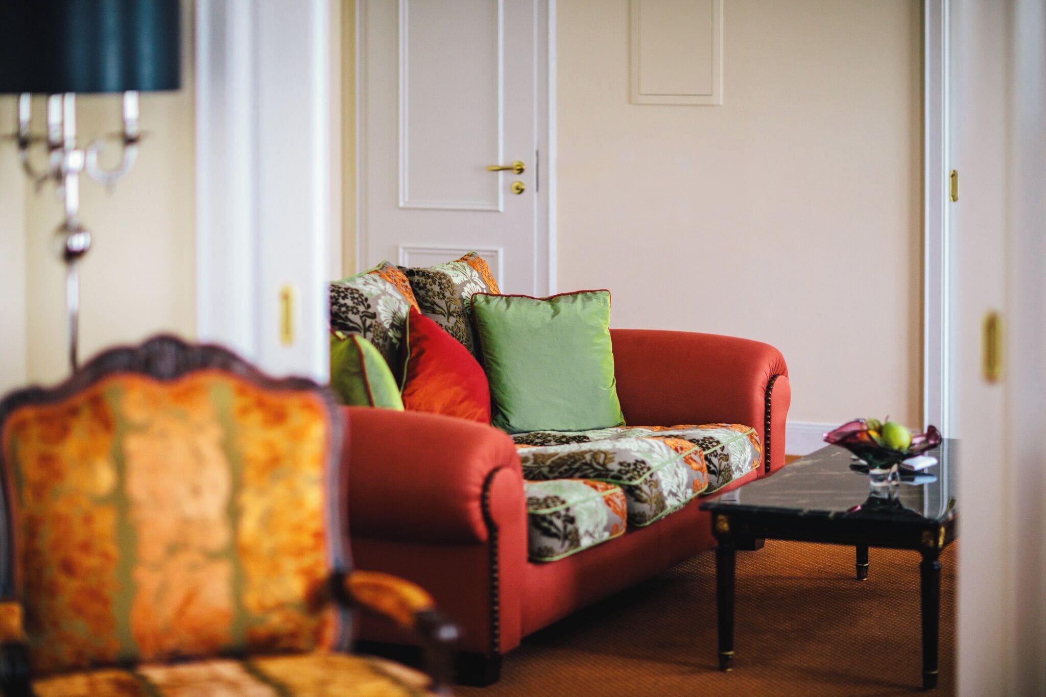 A living room with a red sofa, a patterned armchair, and a small table with a vase.