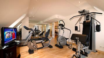 Un gimnasio en casa con cinta de correr, elíptica y máquina de pesas.