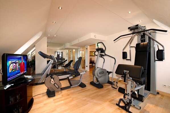 A home gym with a treadmill, elliptical, and weight machine.