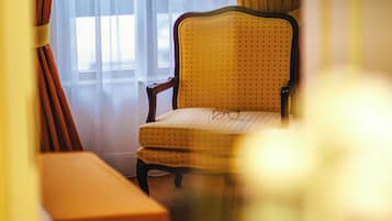 Ein Zimmer mit einem Sessel, einer Bank und einem Fenster mit Vorhängen.