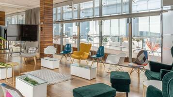 Un interior moderno con un amplio ventanal, un televisor de pantalla plana y diversas opciones de asiento.
