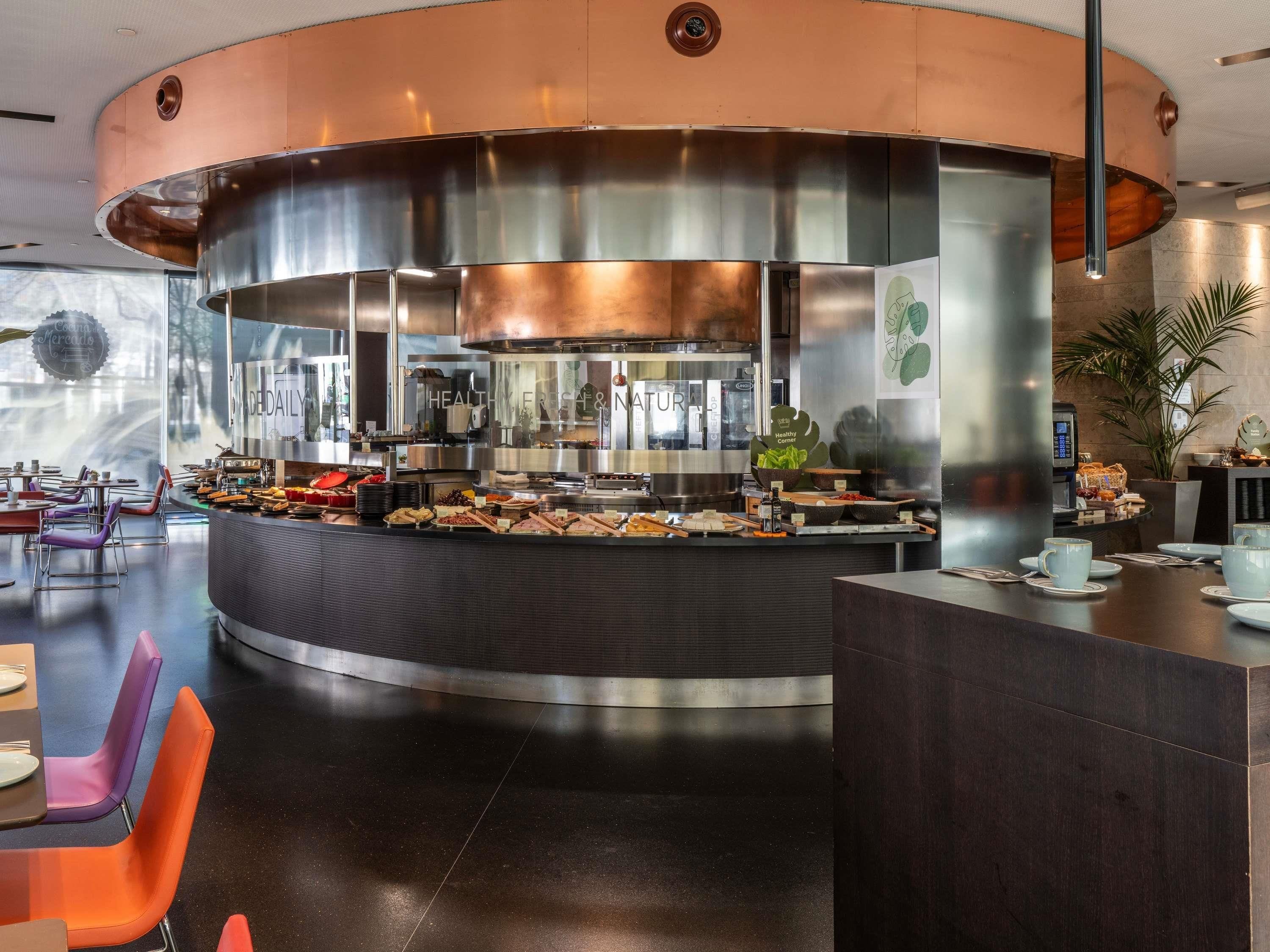 A modern kitchen area with stainless steel appliances, a buffet setup, and seating arrangements.