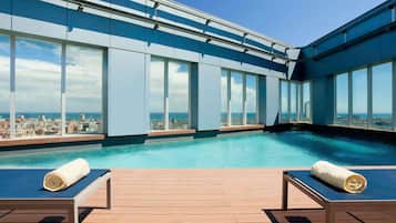 Een seizoensgebonden buitenzwembad, ligstoelen bij het zwembad