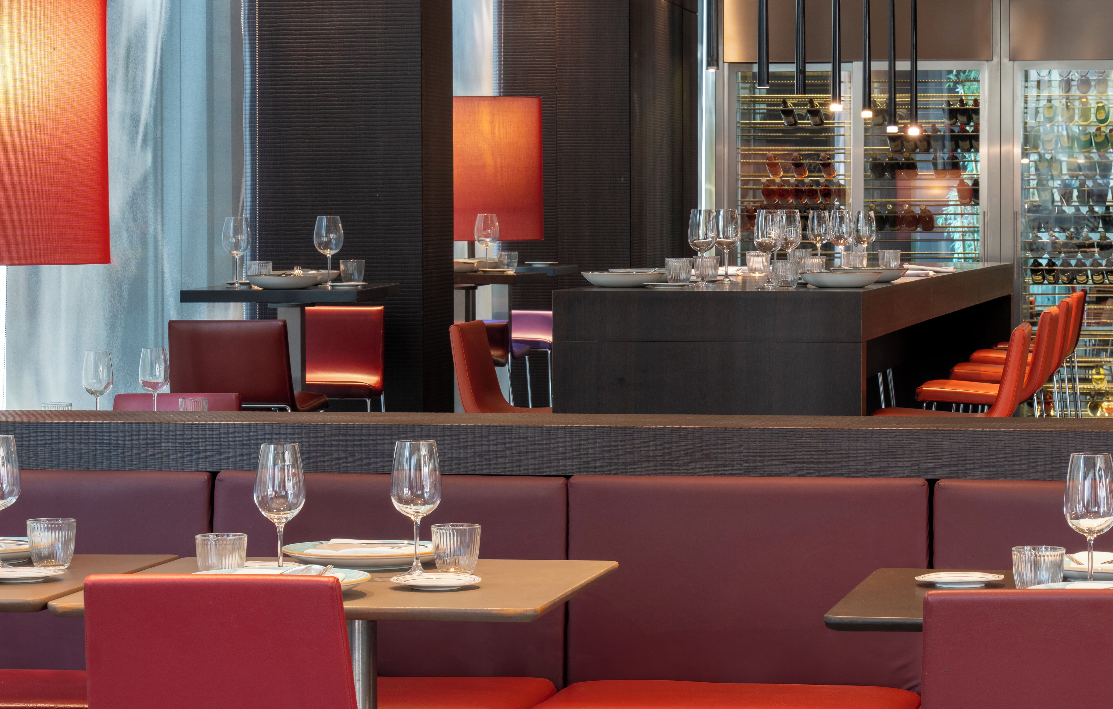 A modern restaurant with red seating and a bar area.