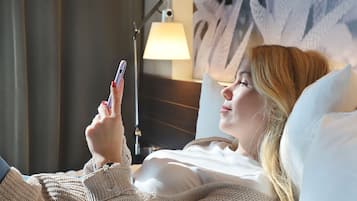 A person lying in bed, holding a smartphone.