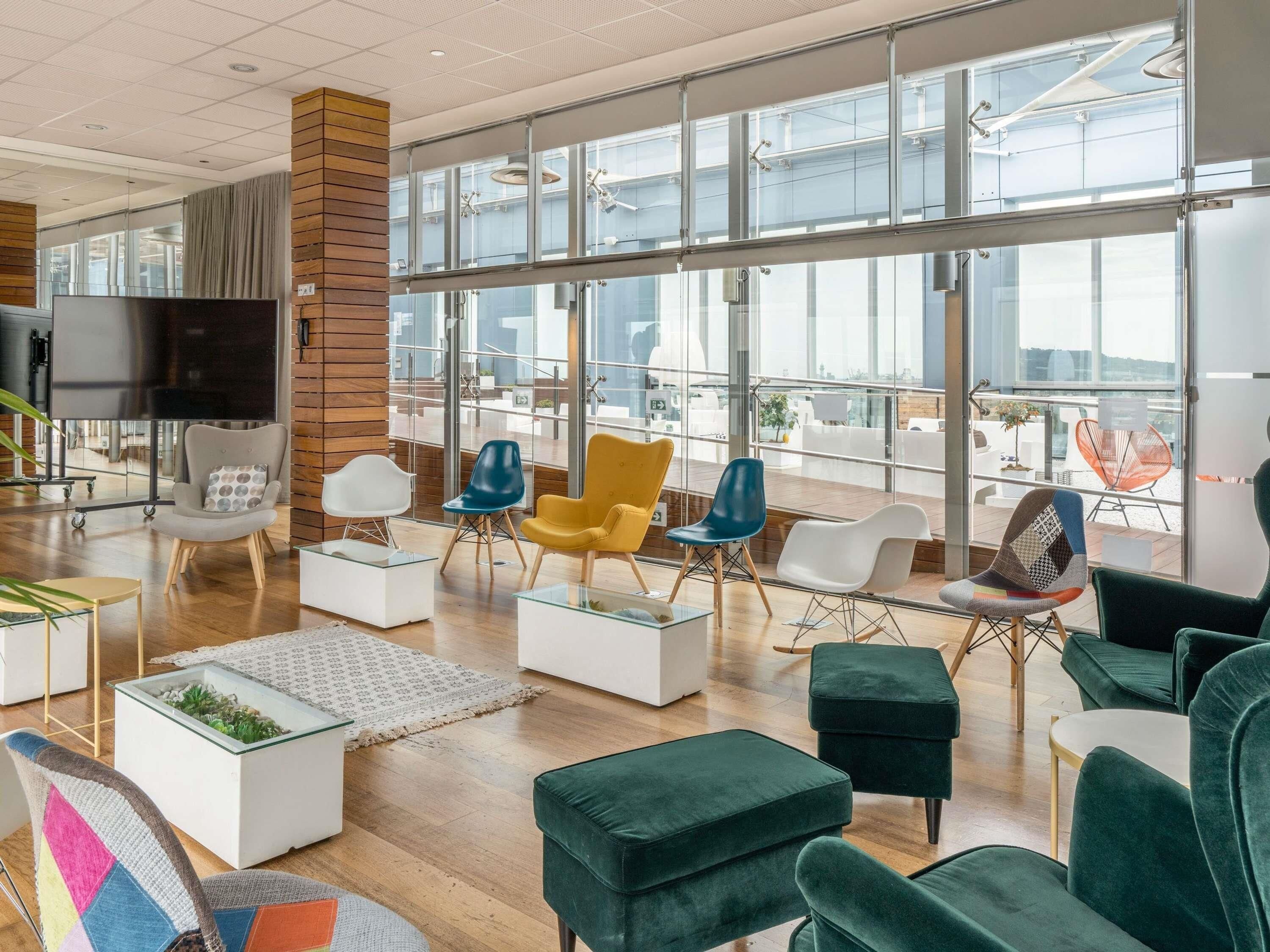 Un interior moderno con un amplio ventanal, un televisor de pantalla plana y diversas opciones de asiento.