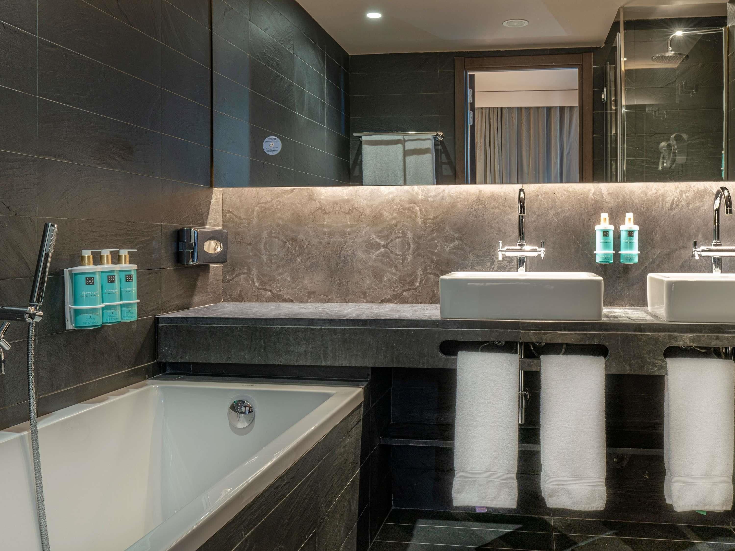 A modern bathroom with a bathtub, two sinks, and a shower.