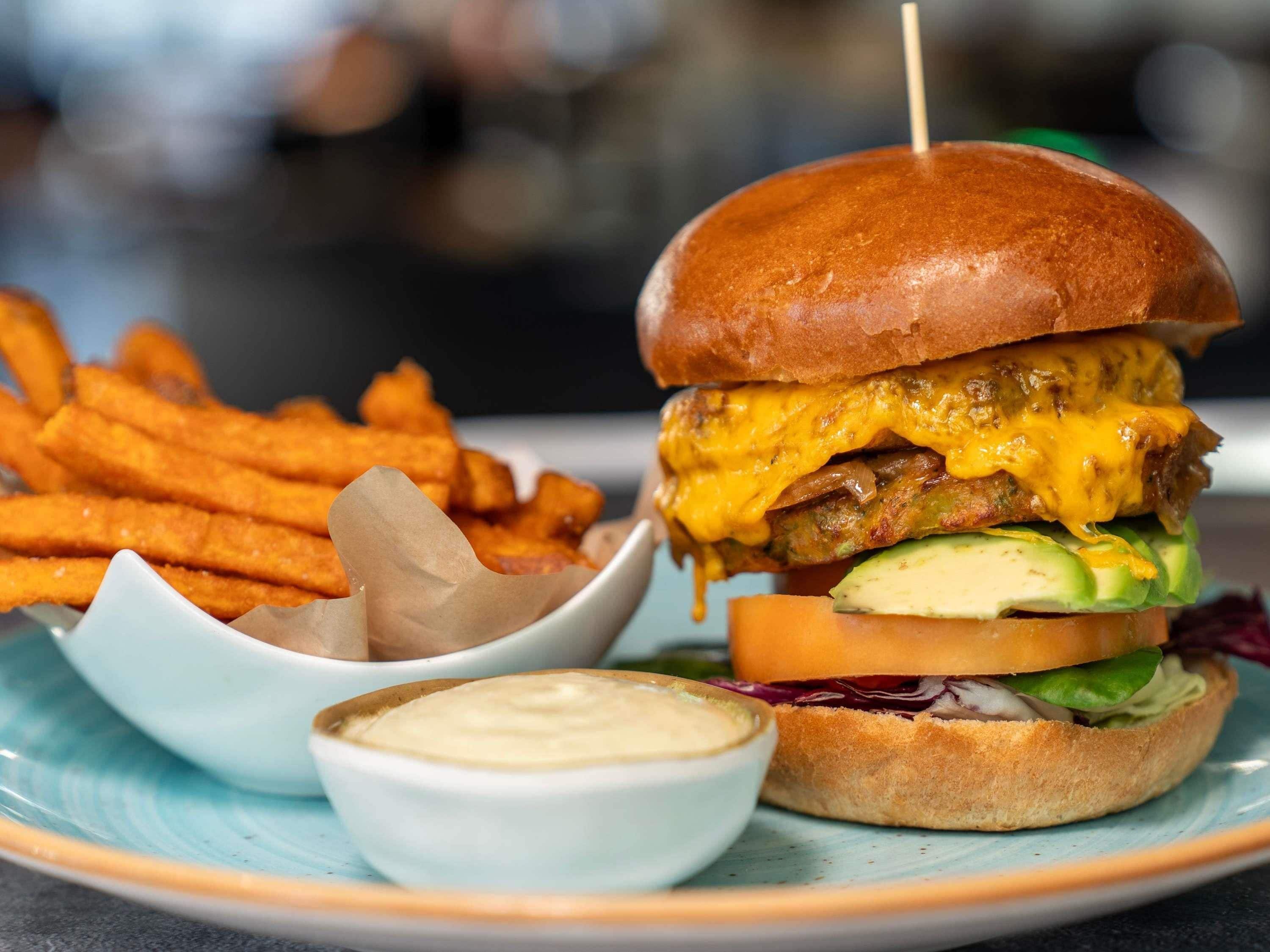 A burger with a bun, cheese, lettuce, tomato, and a side of fries.