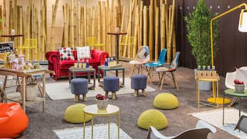 Um interior moderno com decoração em bambu, um sofá vermelho, cadeiras coloridas e uma pequena mesa com garrafas.