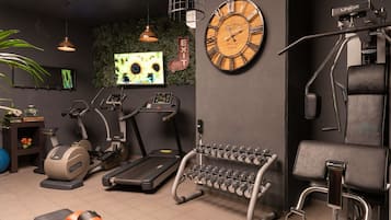 Une salle de sport équipée de matériel d’exercice, avec une horloge murale et un écran de télévision.