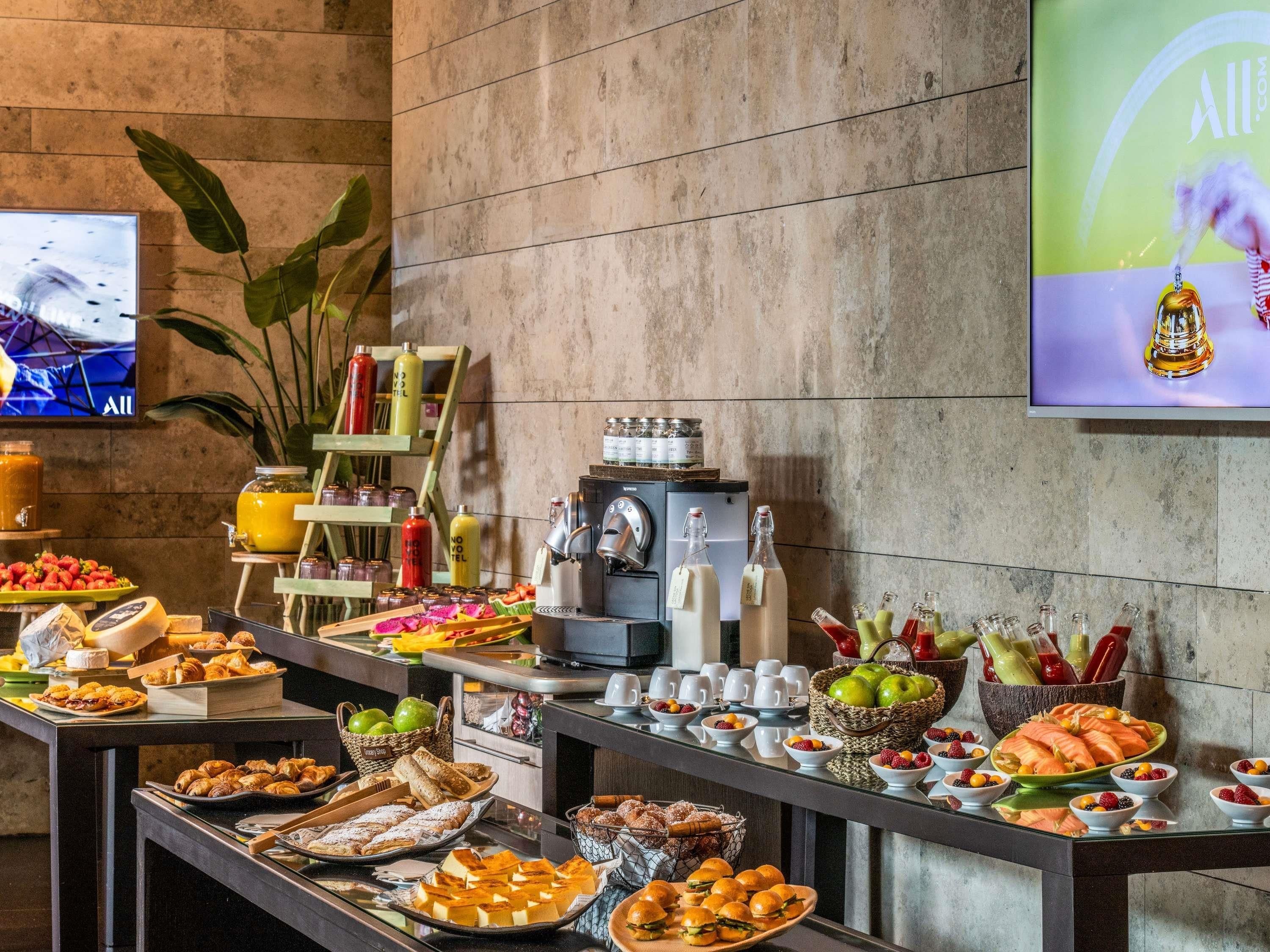 A buffet setup with various food items and beverages, including fruits, pastries, and a coffee machine.