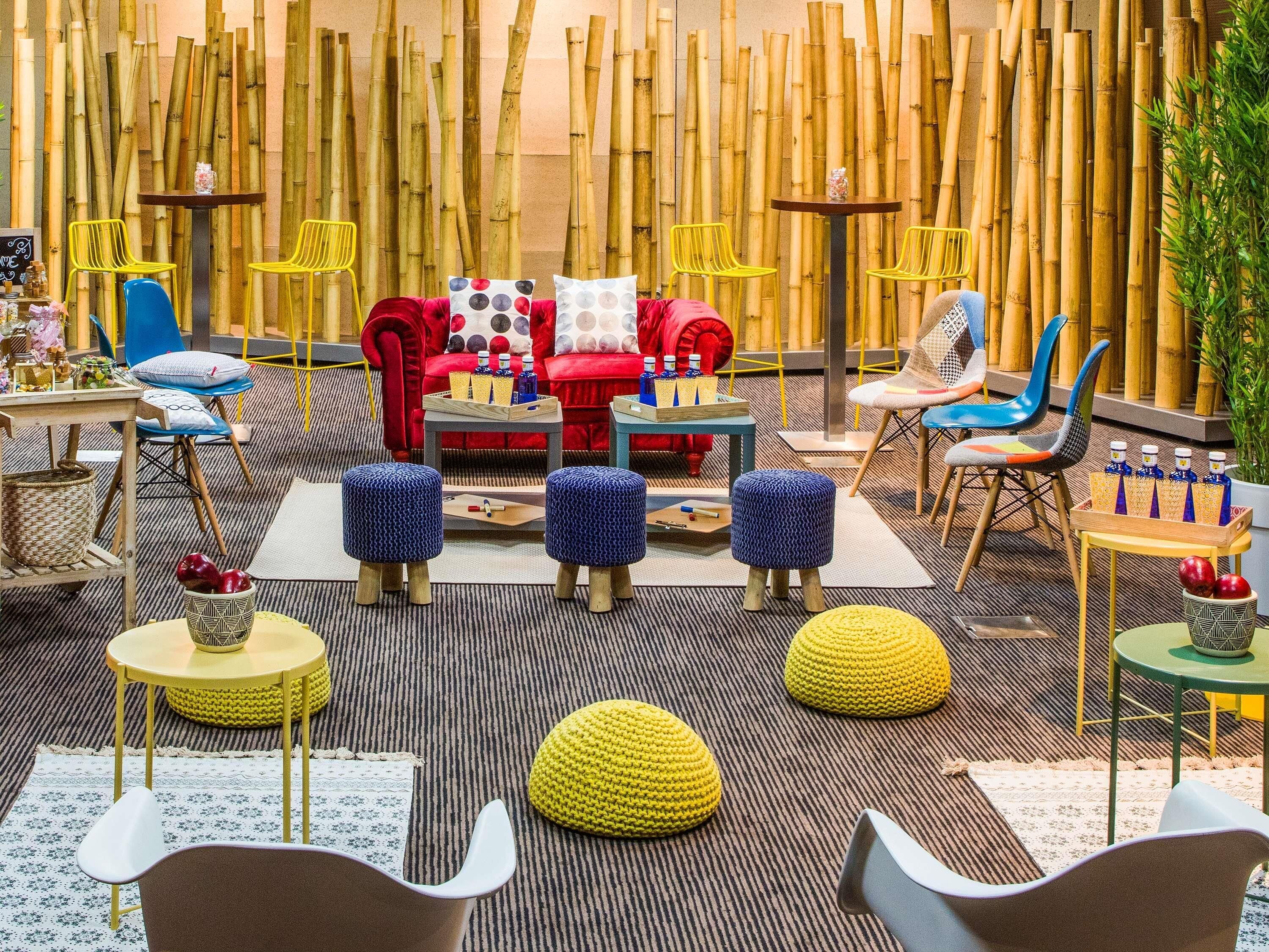 A modern lounge area with a red sofa, yellow chairs, and a bamboo wall.
