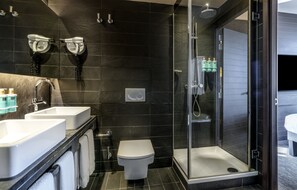 Ein modernes Badezimmer mit zwei Waschbecken, einer Toilette und einer Duschkabine.