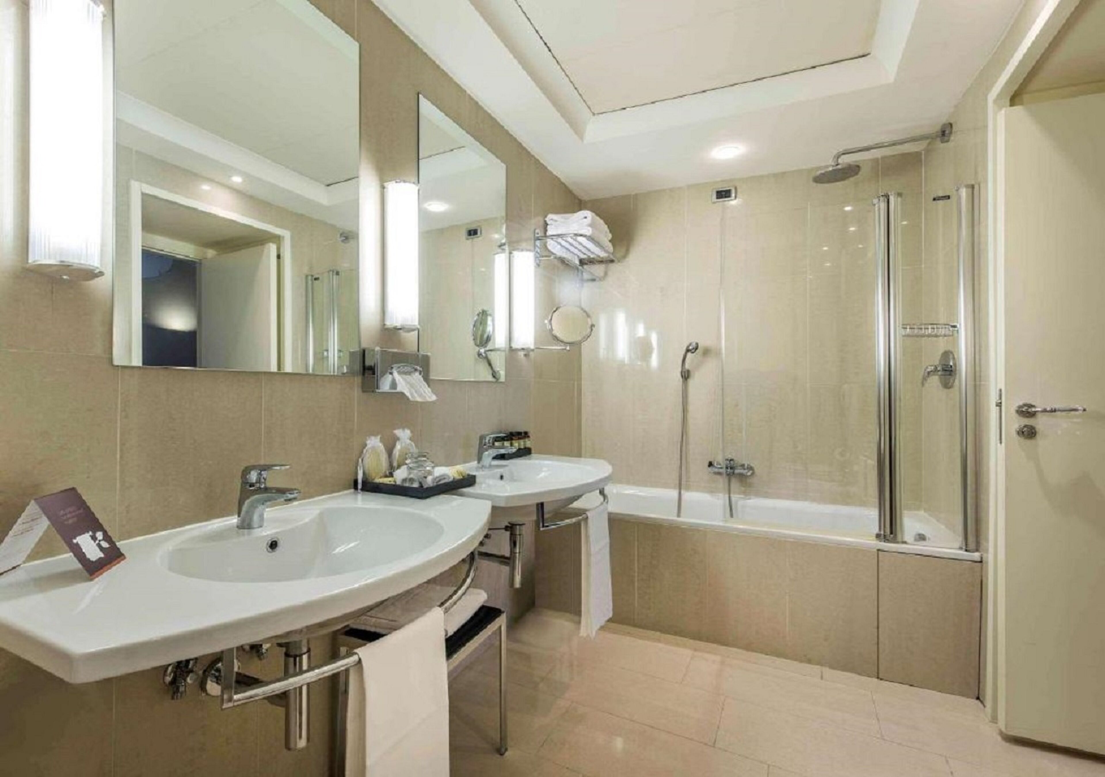 Un baño moderno con dos lavamanos, un espejo grande, una ducha y una puerta.