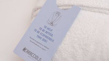 A folded white towel with a tag attached. The tag has text and a small illustration.