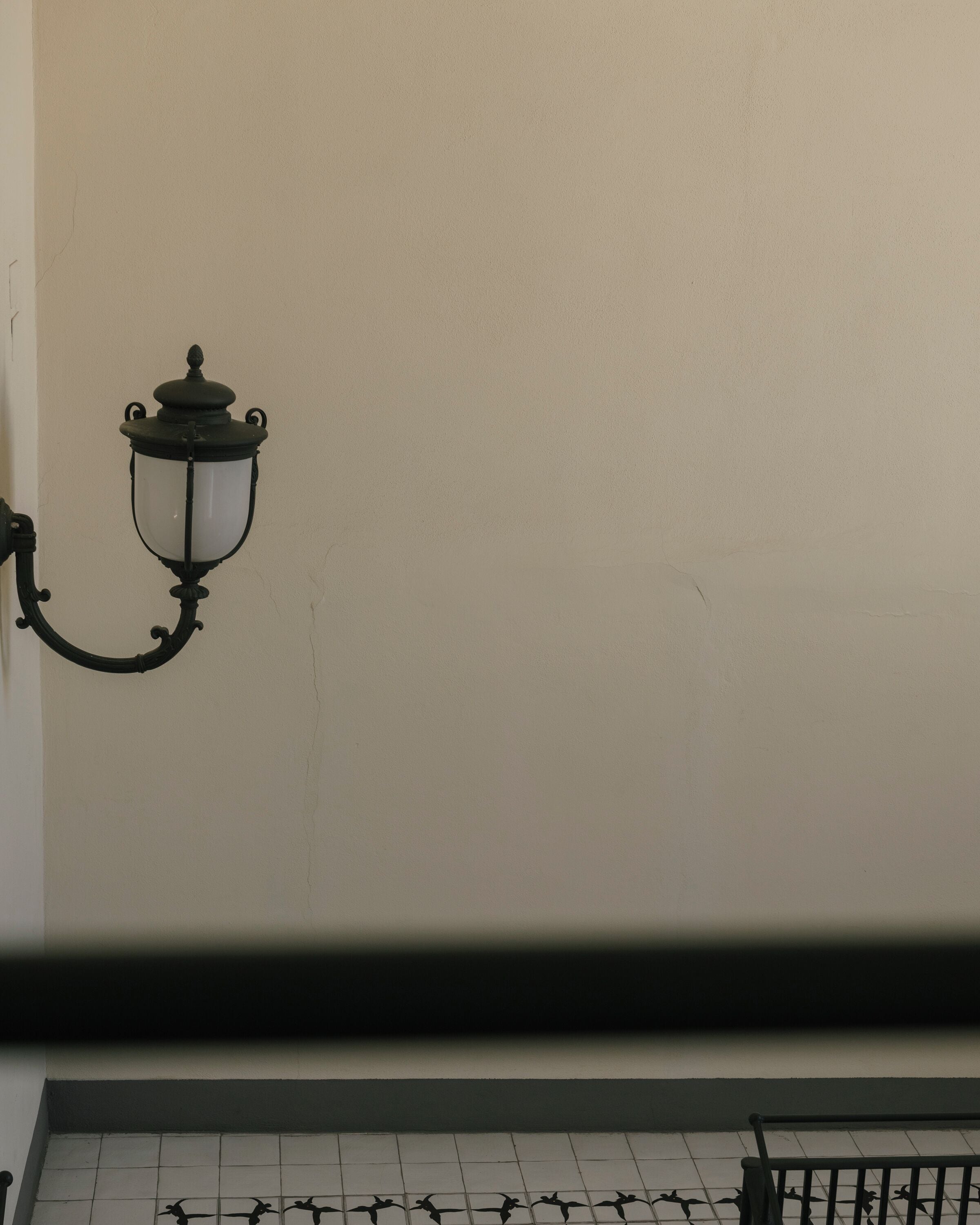 A wall-mounted light fixture with a curved design and a glass enclosure.