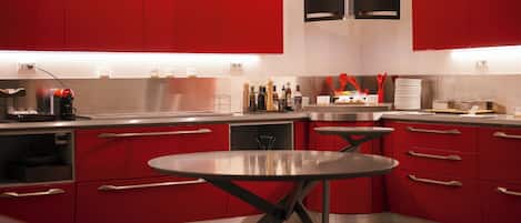 A modern kitchen with red cabinets, stainless steel appliances, and a central island.