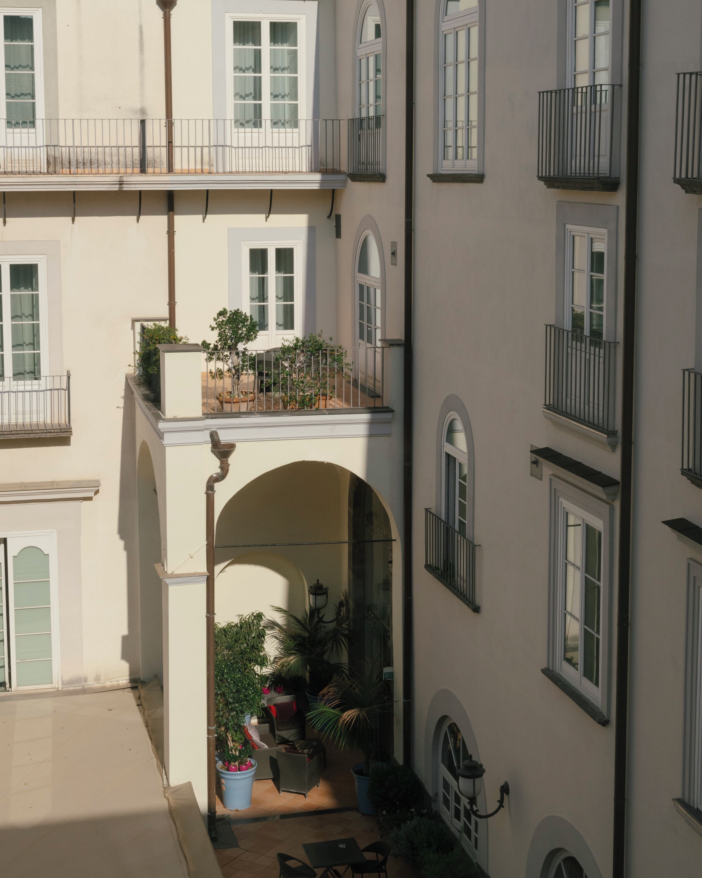 A multi-story building with balconies, outdoor seating, and potted plants.